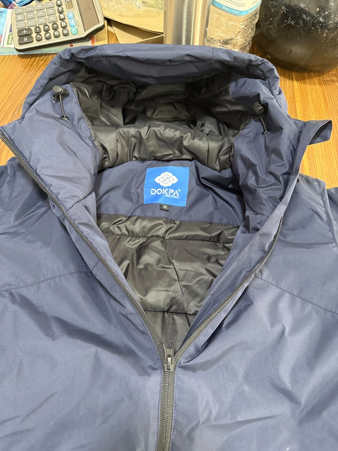 Close view of the blue Dokpa Made in Nepal woven label stitched inside a hood